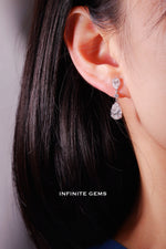 Pear shape lab grown diamond drop earring in 18K white gold, a 0.5ct pear at the lobe linked by a round brilliant to a 1.5ct pear drop, worn on the ear